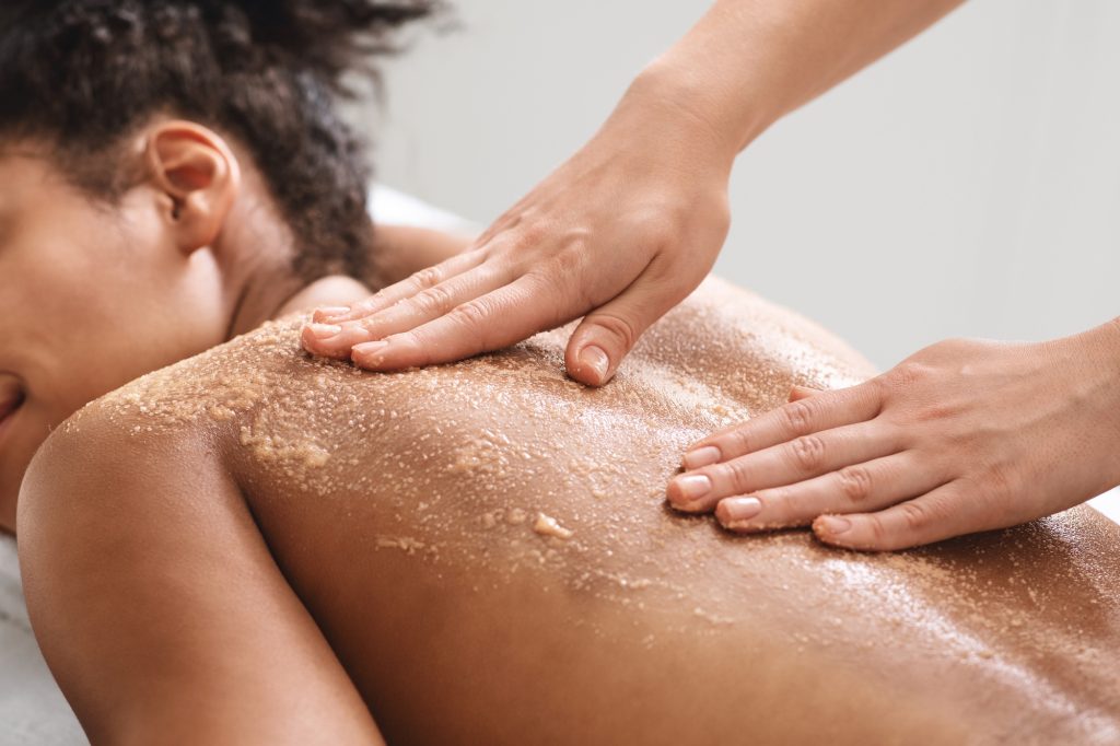 African american lady having skin scrubbing procedure at spa salon